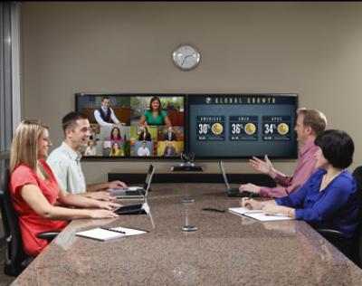 People in a conference room using video conferencing technology to conduct a meeting