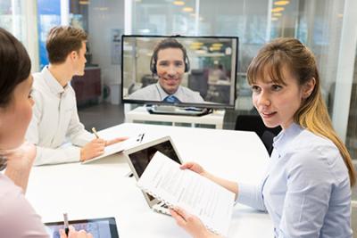 Employees Using Business Phones With Video Conferencing